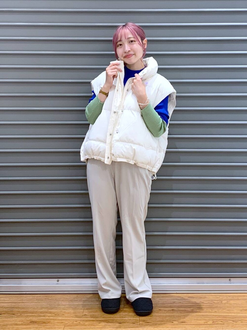 ブラック系のショルダーバッグ、ブルー系のニット/セーター、ホワイト系のダウンベストを着用したレディースの秋コーディネートの4枚目の写真