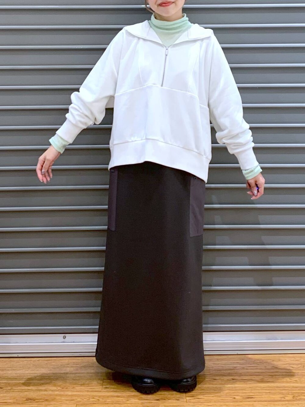 ブラック系のブーツ、シルバー系のショルダーバッグ、グレー系のスカートを着用したレディースの冬コーディネートの3枚目の写真