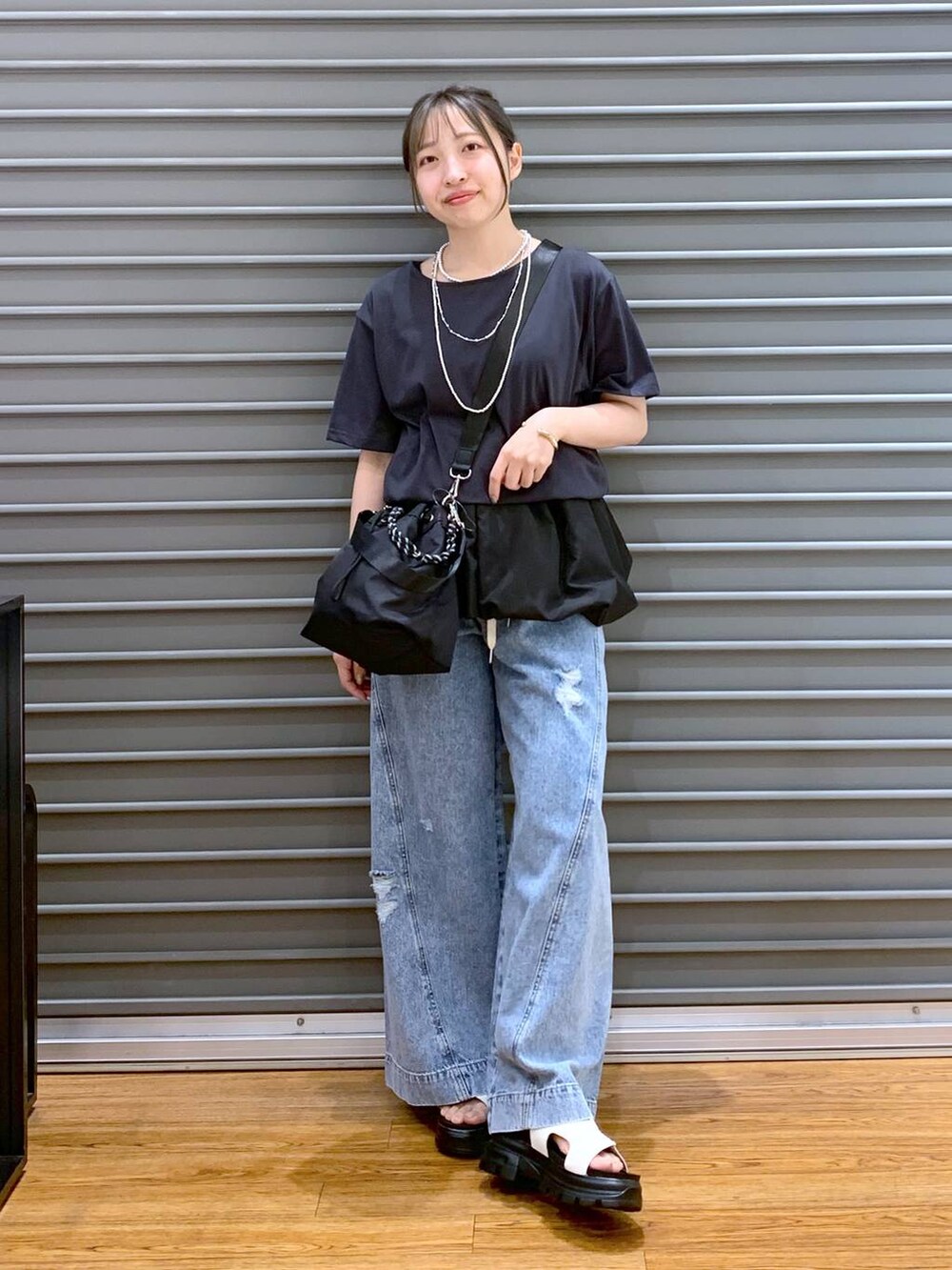 ブルー系のデニムパンツ、ホワイト系のサンダル、ブラック系のショルダーバッグを着用したレディースの秋コーディネートの6枚目の写真