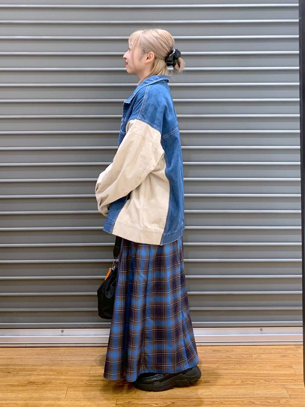 ブラック系のショルダーバッグ、ブラック系のスニーカー、ブルー系のカバーオールを着用したレディースの秋コーディネートの4枚目の写真