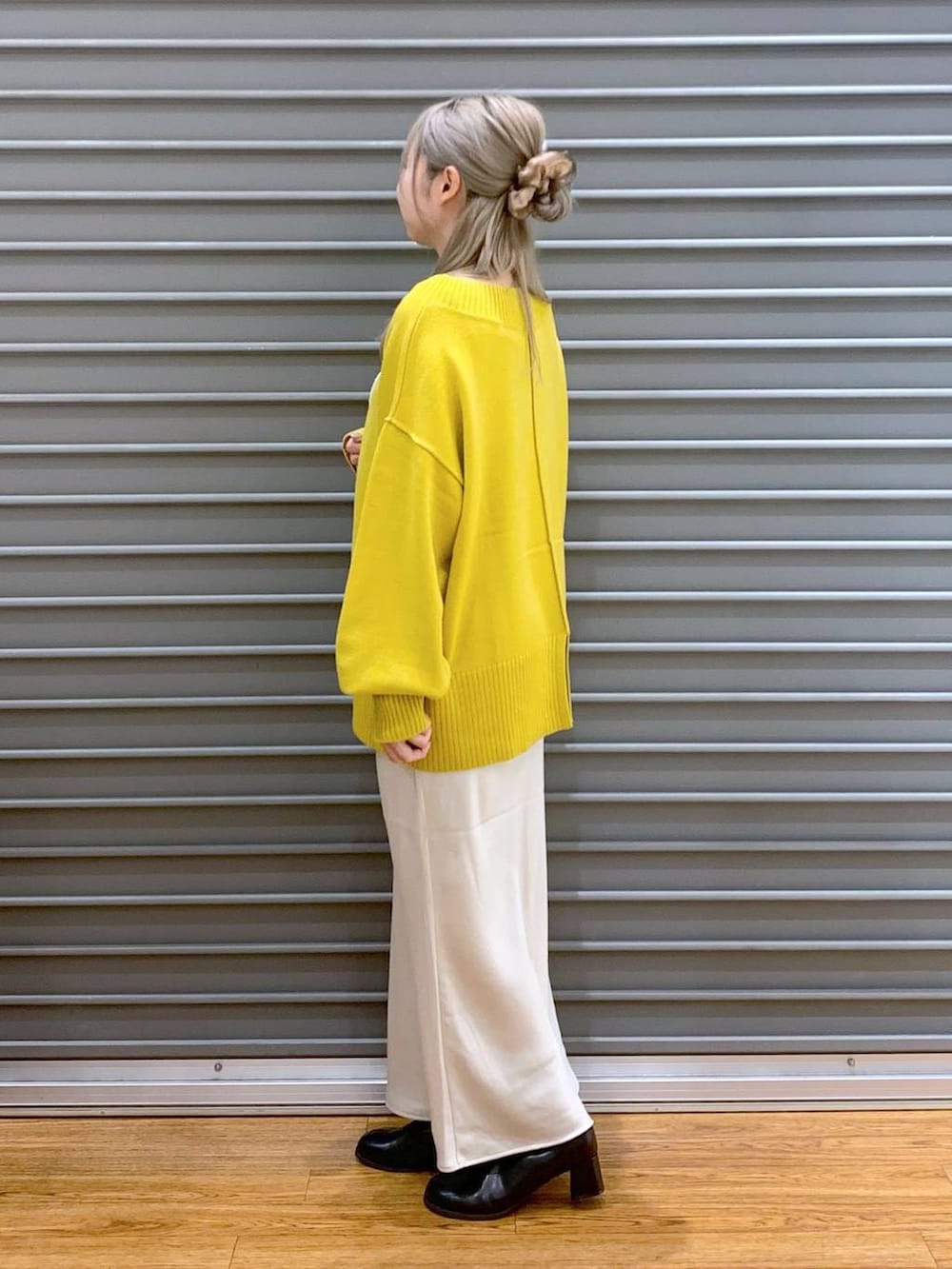 イエロー系のニット/セーター、ホワイト系のスカート、グレー系のショルダーバッグを着用したレディースの冬コーディネートの3枚目の写真