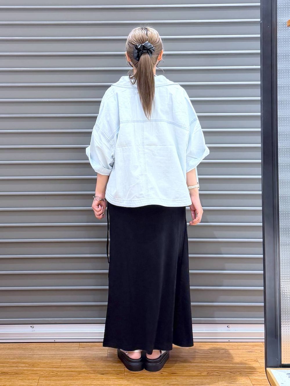 ブラック系のスカート、ホワイト系のTシャツ/カットソー、ブラック系のトートバッグを着用したレディースの夏コーディネートの2枚目の写真