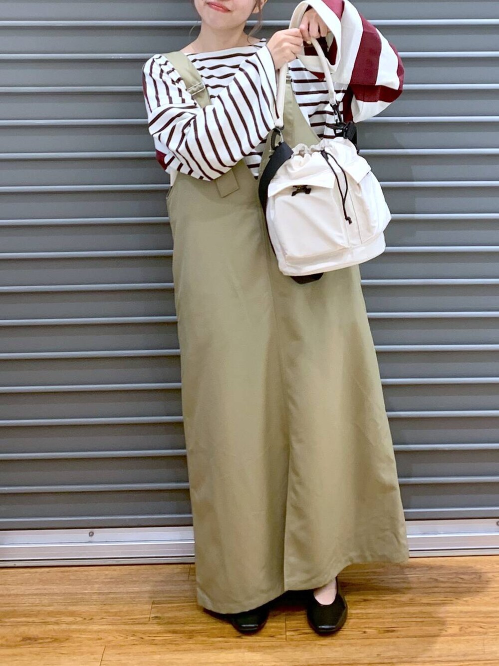 ホワイト系のショルダーバッグ、ブラック系のパンプス、ベージュ系のジャンパースカートを着用したレディースの秋コーディネートの5枚目の写真