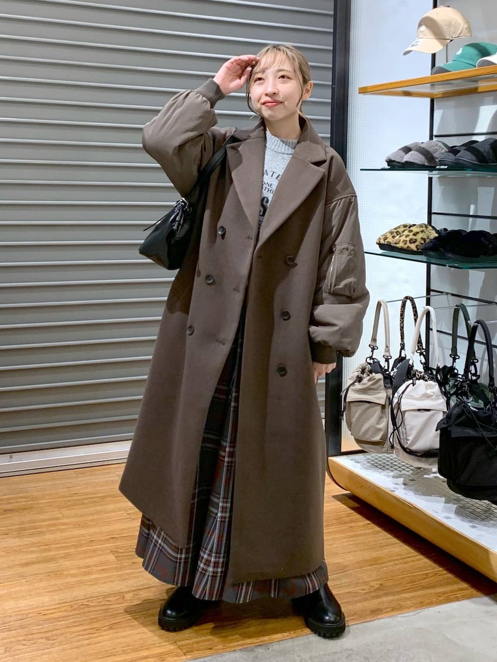 ブラック系のブーツ、グレー系のスカート、ブラック系のショルダーバッグを着用したレディースの冬コーディネートの6枚目の写真