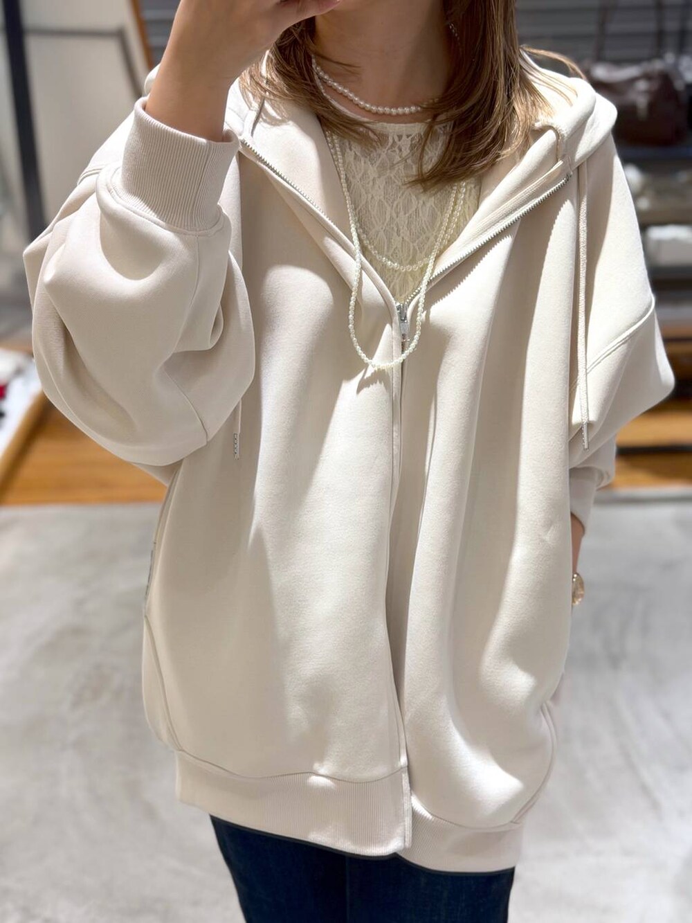 ホワイト系のパーカー、ブルー系のデニムパンツ、ホワイト系のTシャツ/カットソーを着用したレディースの春コーディネートの3枚目の写真