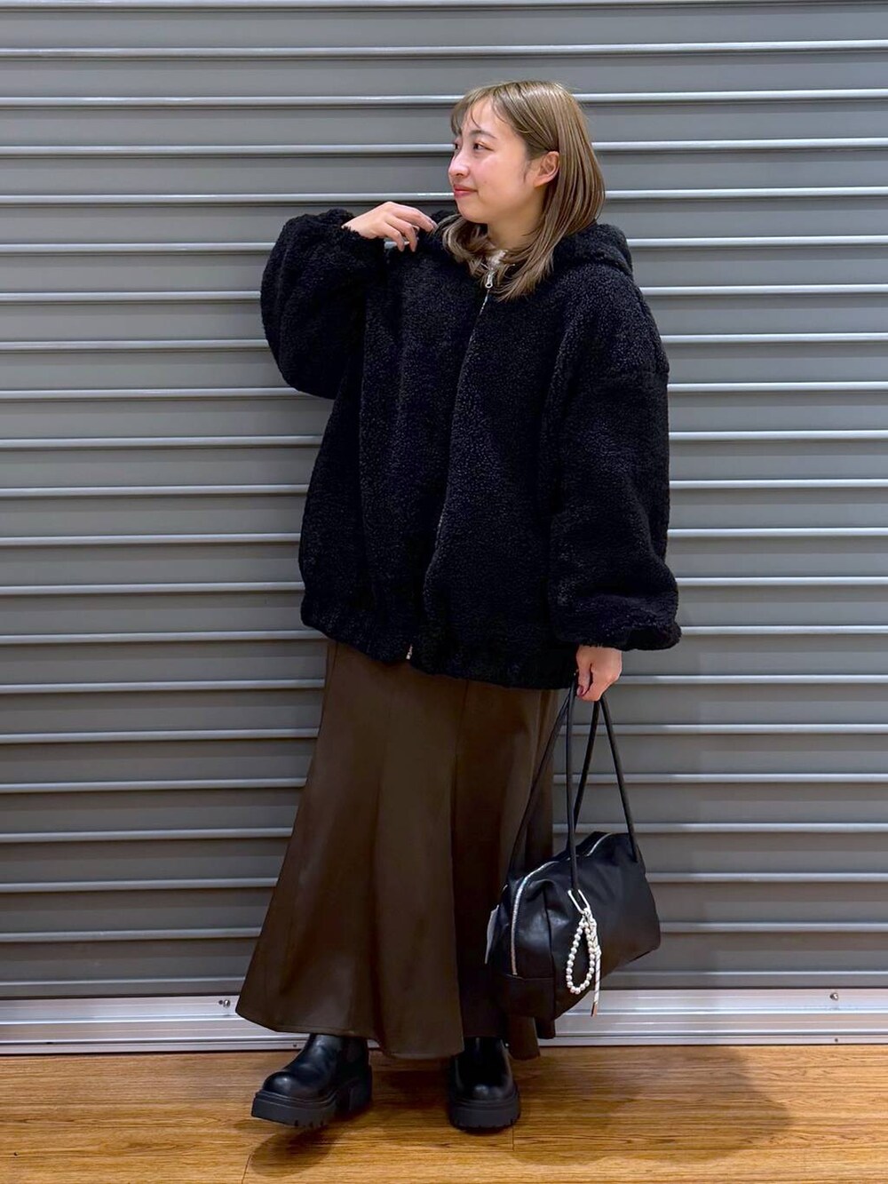 ブラック系のブーツ、ブラウン系のスカート、ブラック系のボストンバッグを着用したレディースの冬コーディネートの5枚目の写真