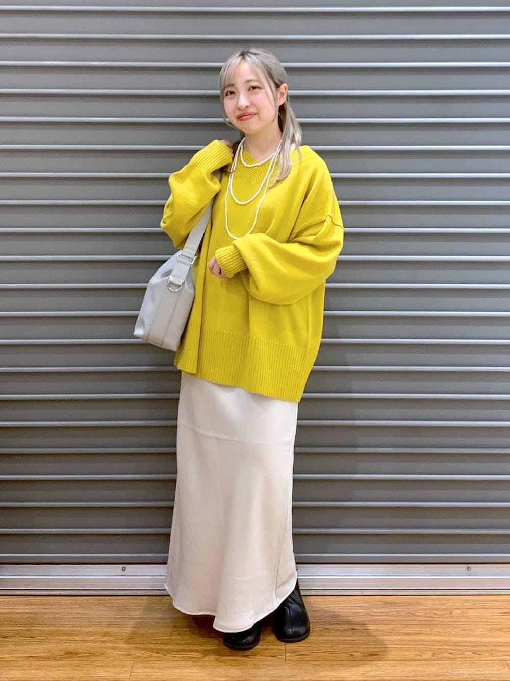 イエロー系のニット/セーター、ホワイト系のスカート、グレー系のショルダーバッグを着用したレディースの冬コーディネートの6枚目の写真