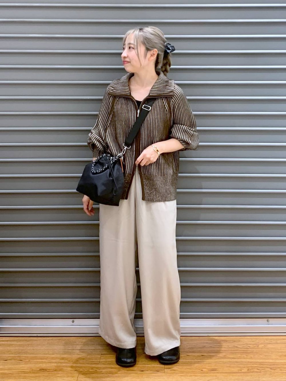 ブラック系のショルダーバッグ、ブラウン系のカーディガン/ボレロ、ブラック系のブーツを着用したレディースの冬コーディネートの5枚目の写真