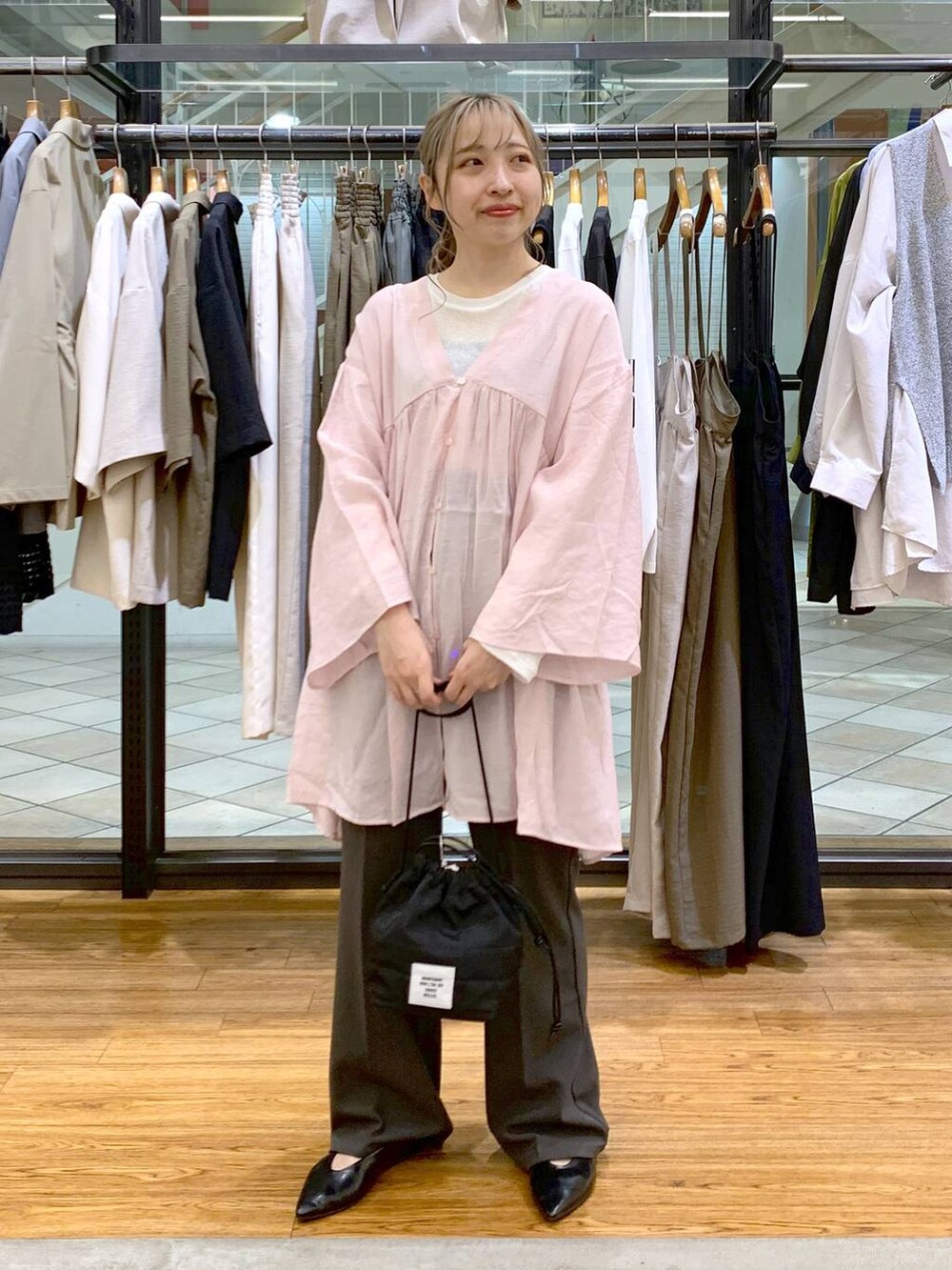 ホワイト系のTシャツ/カットソー、グレー系のスラックス、ブラック系のショルダーバッグを着用したレディースの春コーディネートの6枚目の写真