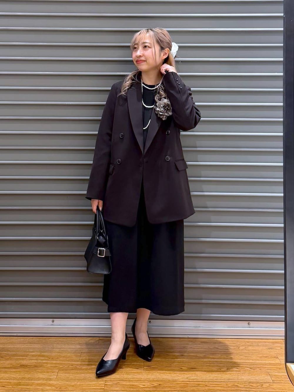 ブラック系のテーラードジャケット、ブラック系のワンピース、ブラック系のショルダーバッグを着用したレディースの冬コーディネートの7枚目の写真