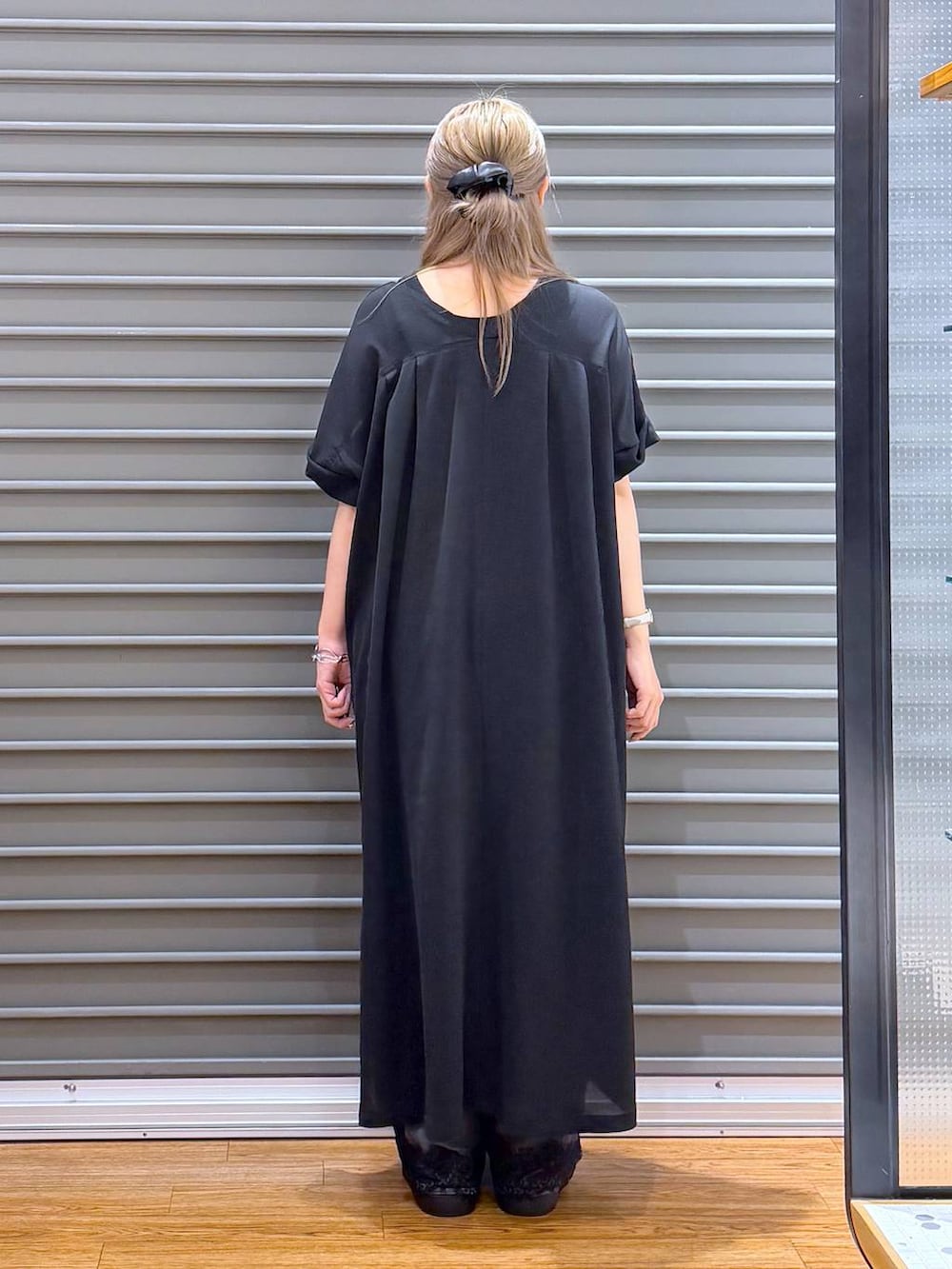 ブラック系のショルダーバッグ、ホワイト系のサンダル、ブラック系のワンピースを着用したレディースの夏コーディネートの2枚目の写真