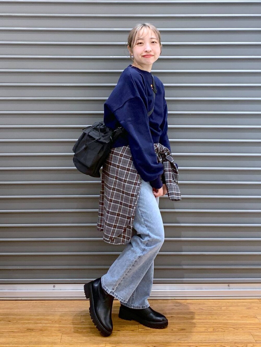 ブラック系のショルダーバッグ、ブルー系のデニムパンツ、ブラック系のブーツを着用したレディースの冬コーディネートの5枚目の写真