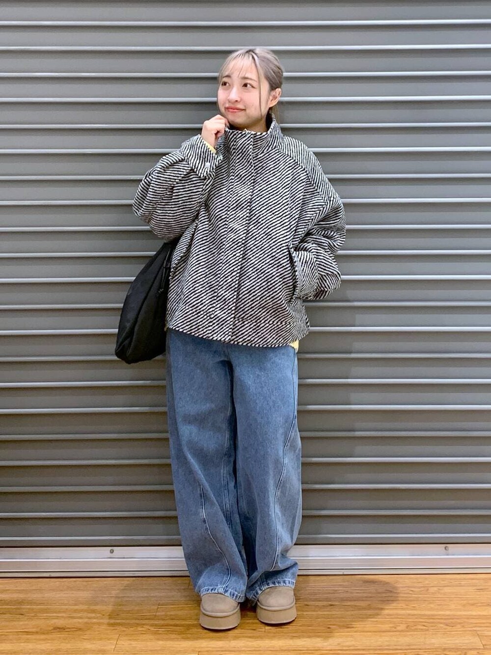 イエロー系のニット/セーター、ブラック系のブルゾン、ブラック系のトートバッグを着用したレディースの冬コーディネートの8枚目の写真