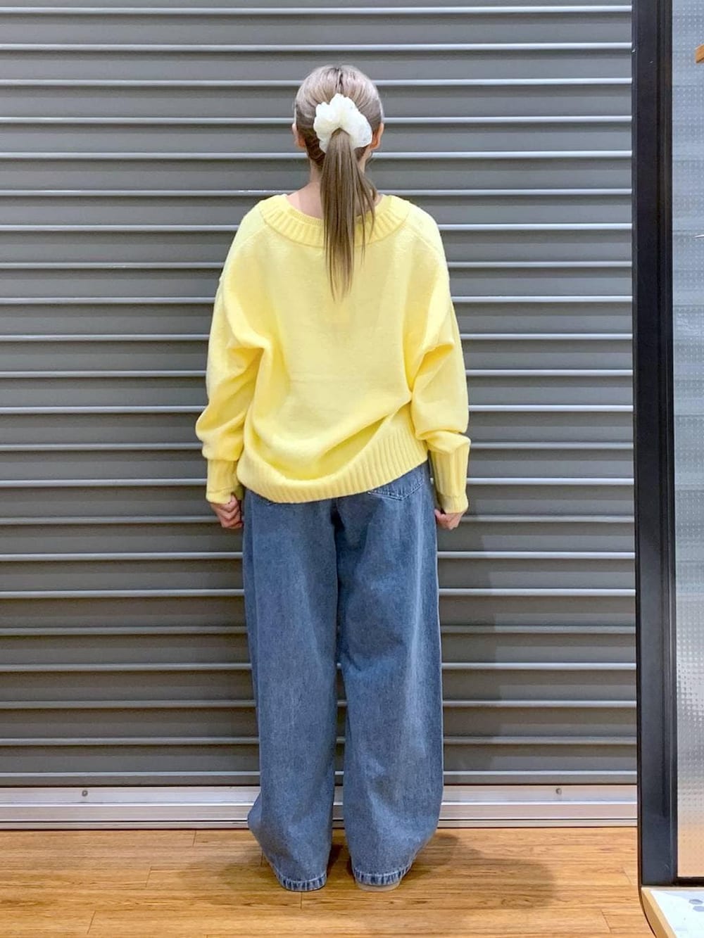 グレー系のショルダーバッグ、イエロー系のニット/セーター、ブルー系のデニムパンツを着用したレディースの冬コーディネートの2枚目の写真