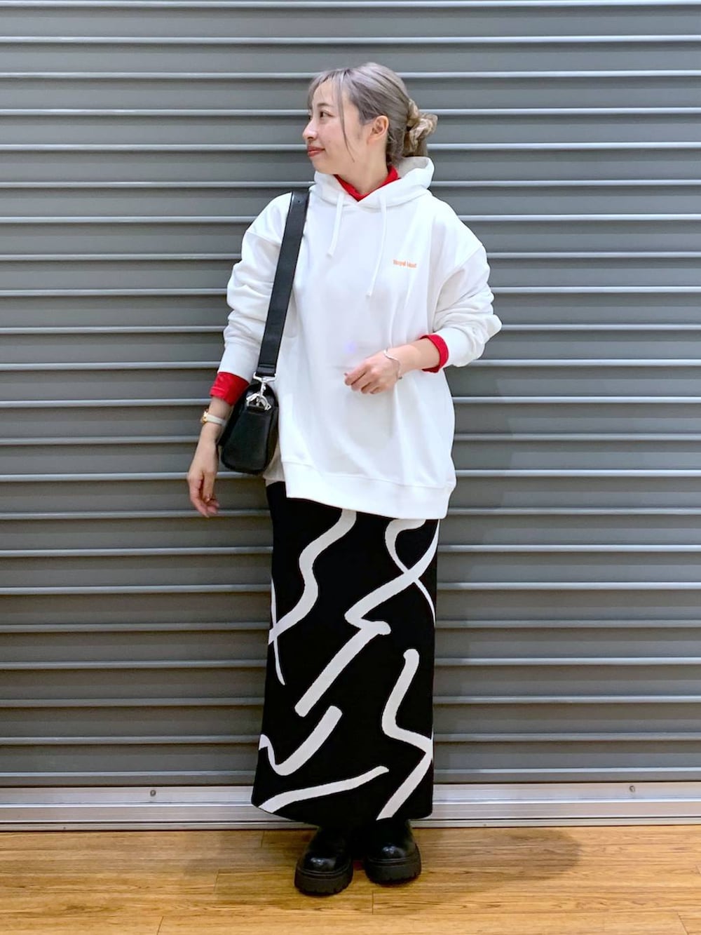 ブラック系のスカート、ブラック系のショルダーバッグ、ブラック系のブーツを着用したレディースの冬コーディネートの7枚目の写真