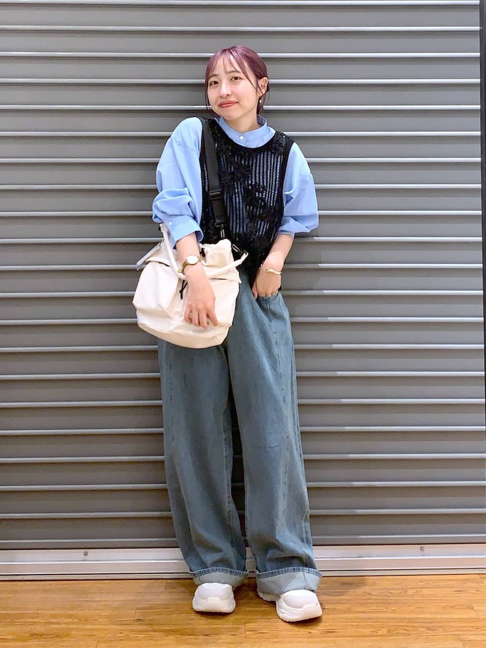 ホワイト系のショルダーバッグ、ブルー系のデニムパンツ、ホワイト系のスニーカーを着用したレディースの秋コーディネートの3枚目の写真