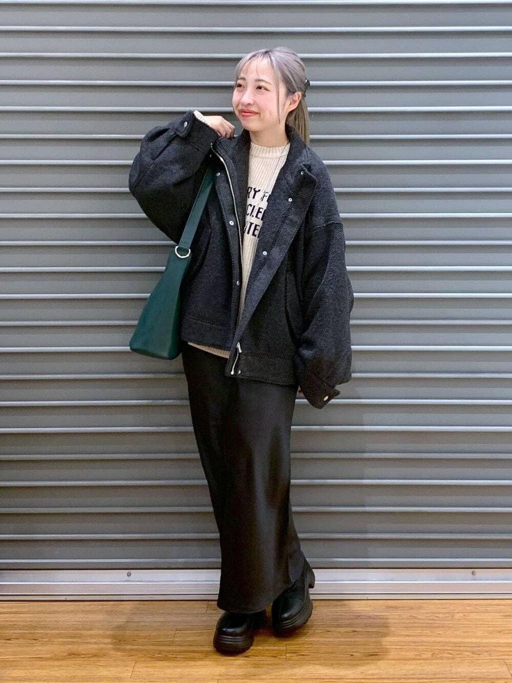 ブラック系のスカート、グリーン系のショルダーバッグ、ブラック系のブルゾンを着用したレディースの冬コーディネートの6枚目の写真