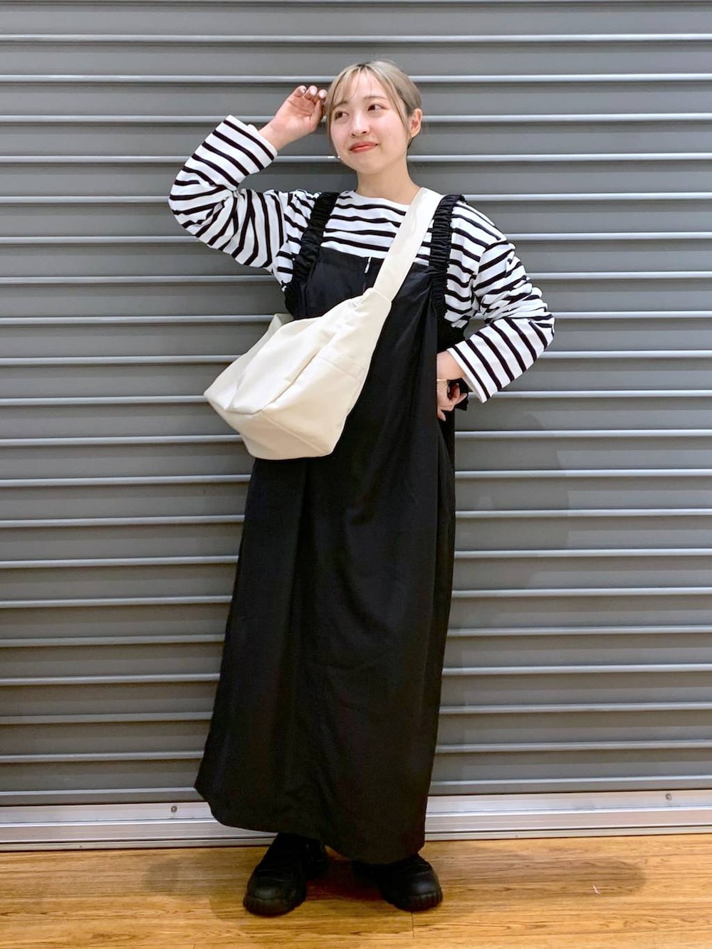 ブルー系のTシャツ/カットソー、ブラック系のスニーカー、ブラック系のジャンパースカートを着用したレディースの冬コーディネートの3枚目の写真