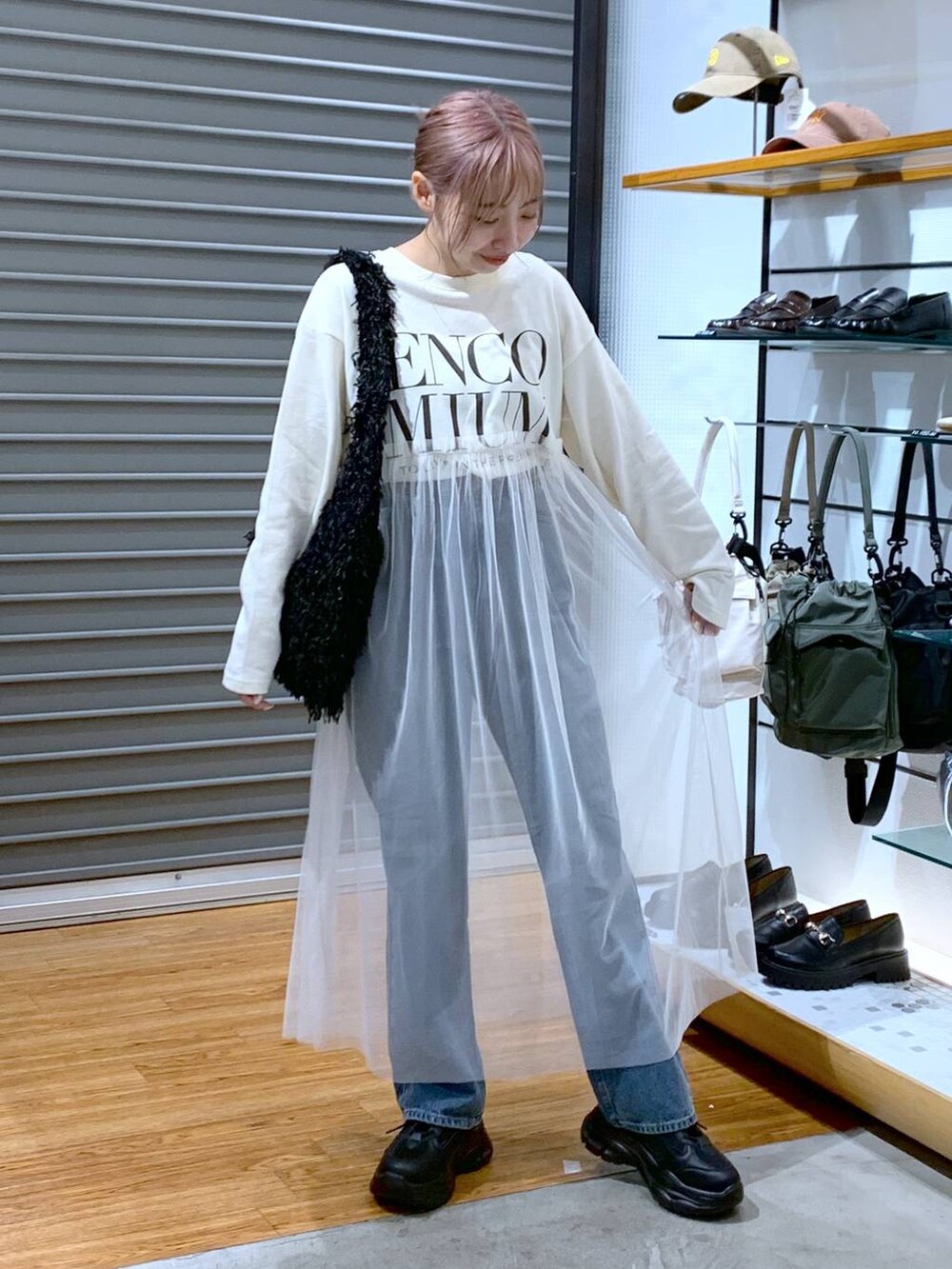 ブラック系のスニーカー、ブルー系のデニムパンツ、ブラック系のショルダーバッグを着用したレディースの秋コーディネートの3枚目の写真