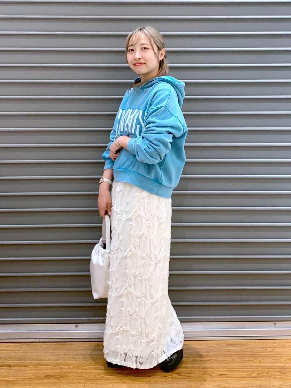 ブルー系のパーカー、ホワイト系のスカート、ブラック系のローファーを着用したレディースの冬コーディネートの3枚目の写真