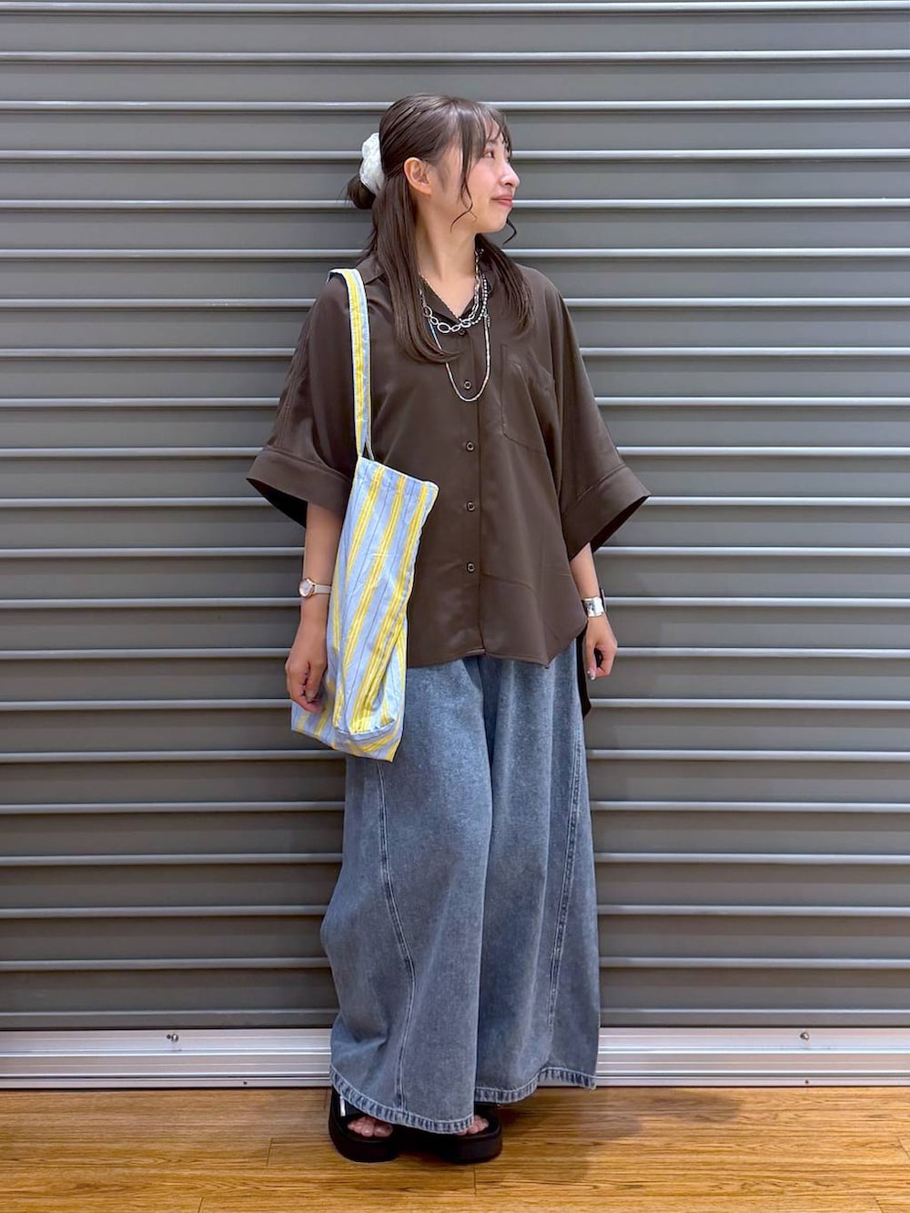 ブルー系のトートバッグ、ブラウン系のシャツ/ブラウス、ブラック系のサンダルを着用したレディースの夏コーディネートの4枚目の写真