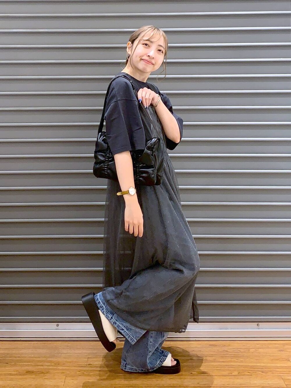 ブラック系のショルダーバッグ、ブルー系のデニムパンツ、ホワイト系のサンダルを着用したレディースの秋コーディネートの5枚目の写真