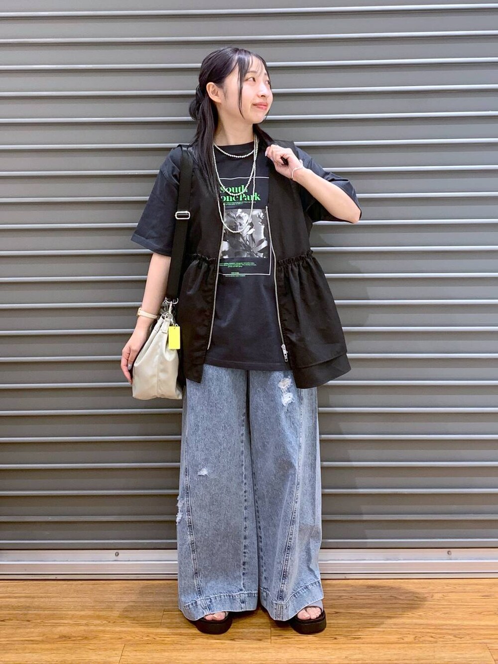 シルバー系のサンダル、ブルー系のデニムパンツ、ブラック系のベストを着用したレディースの夏コーディネートの3枚目の写真