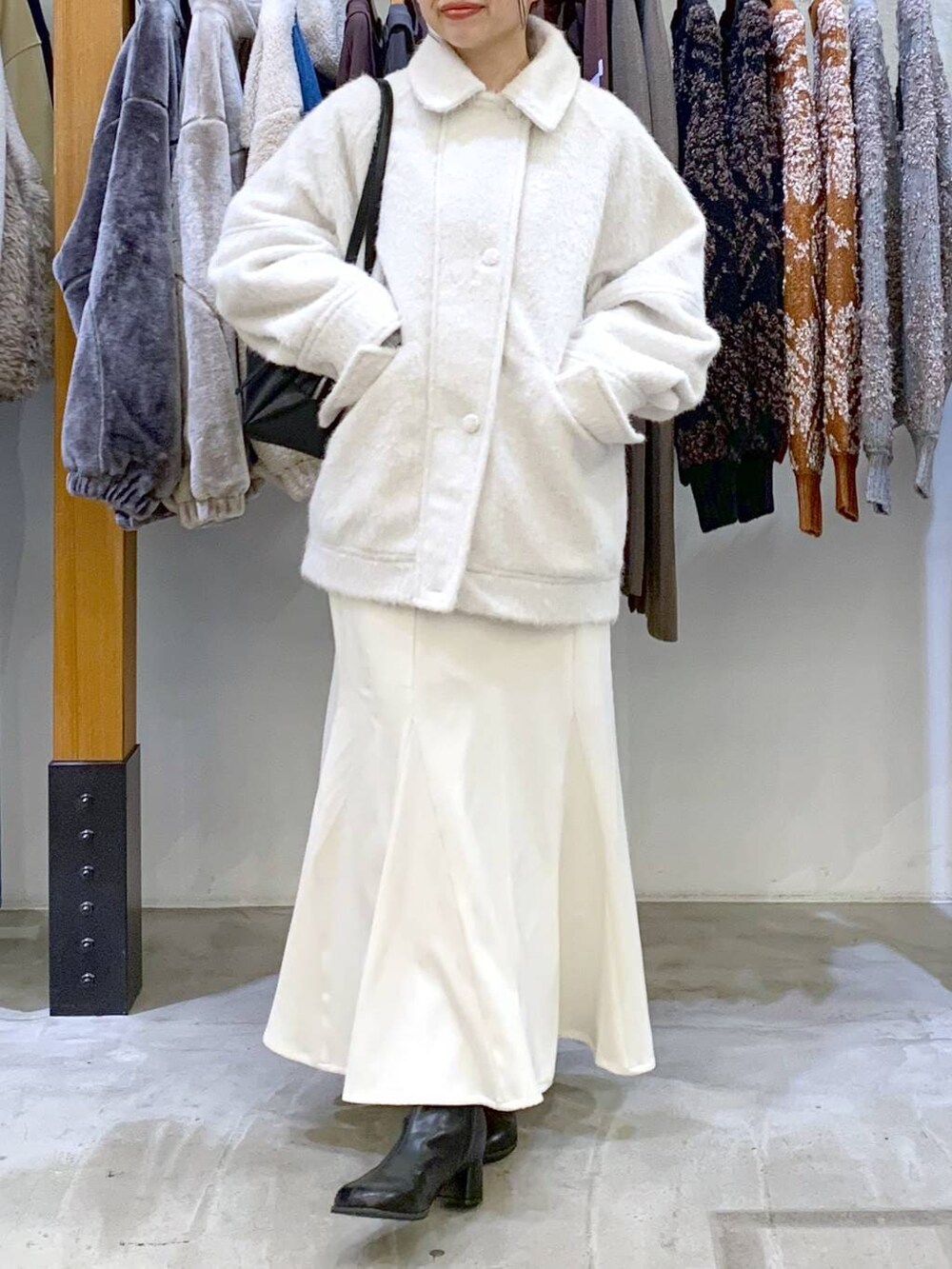 ブラック系のボストンバッグ、ブラック系のブーツ、ホワイト系のブルゾンを着用したレディースの冬コーディネートの6枚目の写真