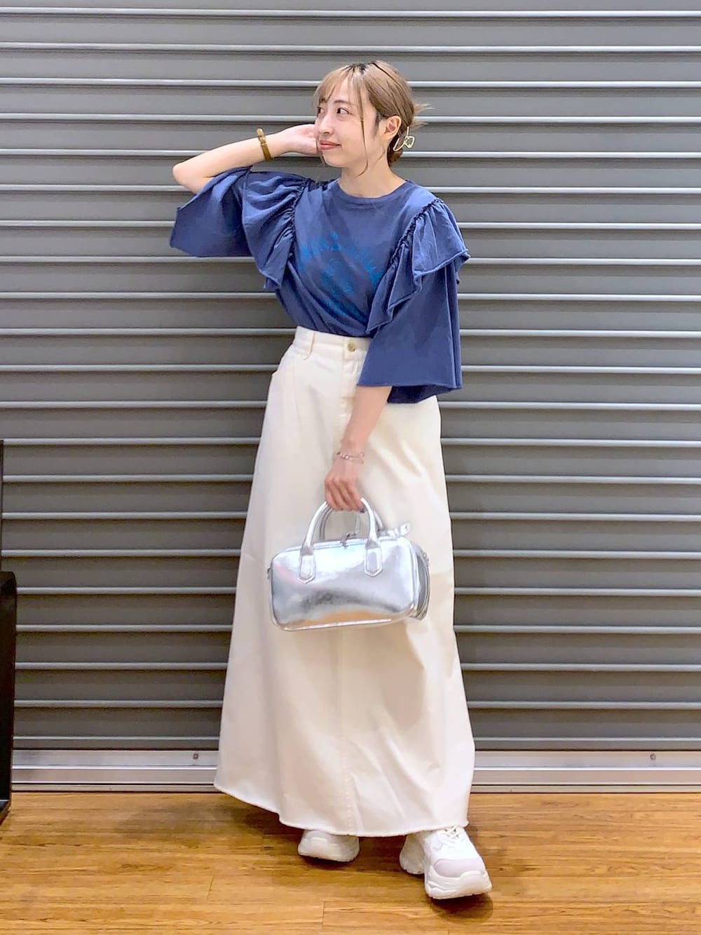 ホワイト系のスカート、ホワイト系のスニーカー、シルバー系のボストンバッグを着用したレディースの夏コーディネートの3枚目の写真