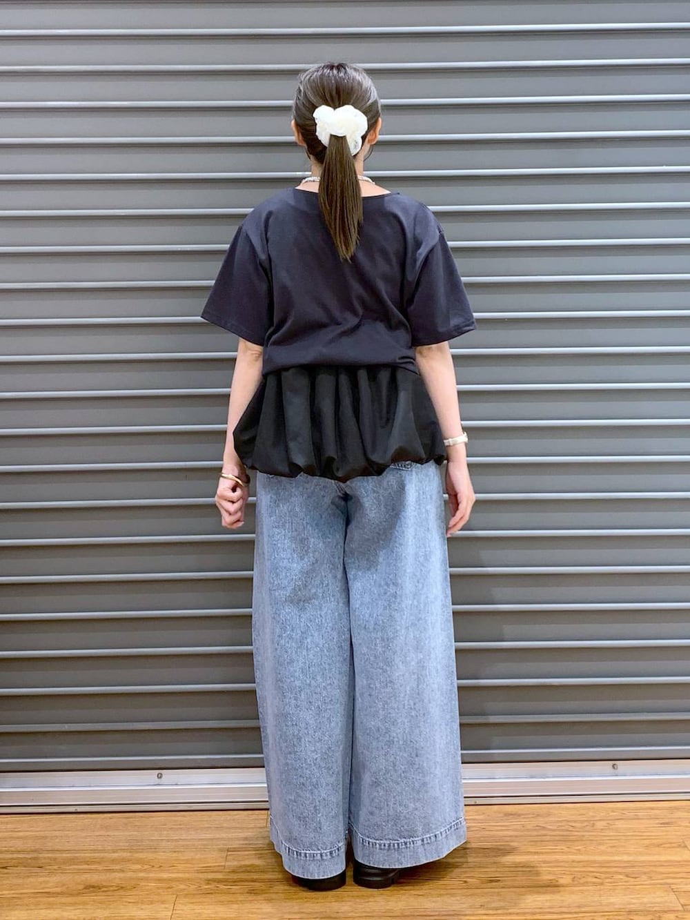 ブルー系のデニムパンツ、ホワイト系のサンダル、ブラック系のショルダーバッグを着用したレディースの秋コーディネートの2枚目の写真