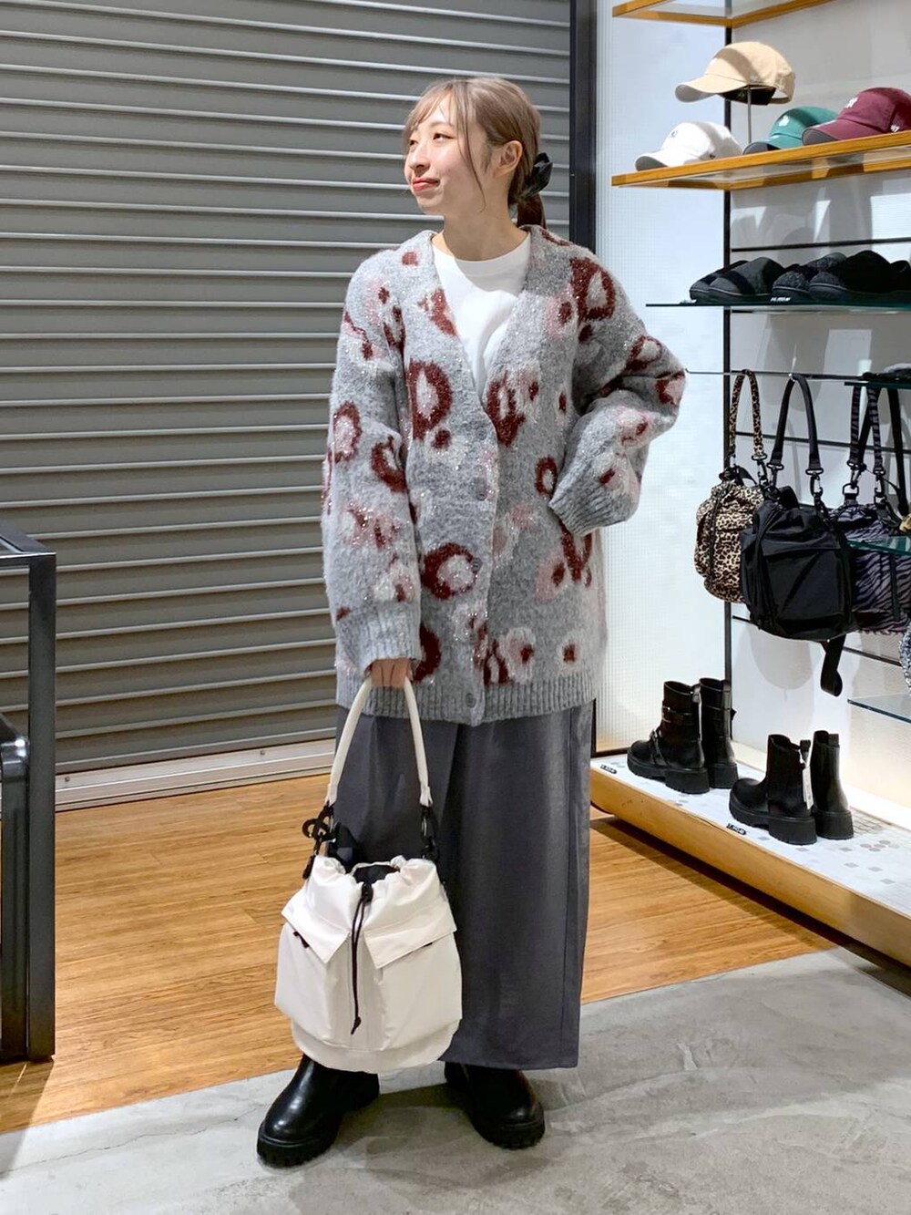 ホワイト系のショルダーバッグ、ブラック系のブーツ、ブラック系のスカートを着用したレディースの冬コーディネートの7枚目の写真