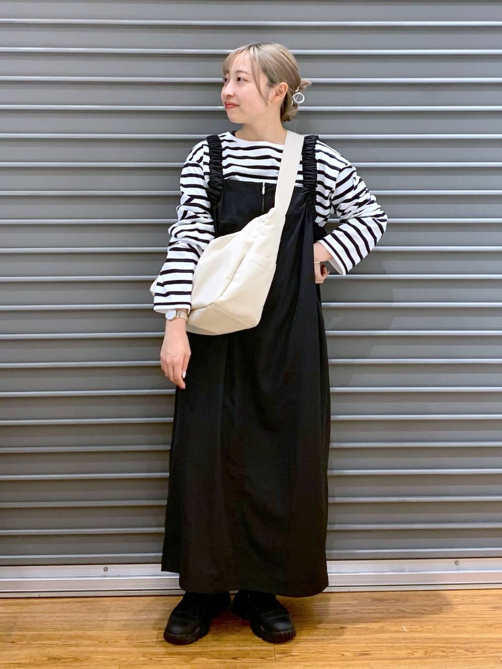 ブルー系のTシャツ/カットソー、ブラック系のスニーカー、ブラック系のジャンパースカートを着用したレディースの冬コーディネートの5枚目の写真