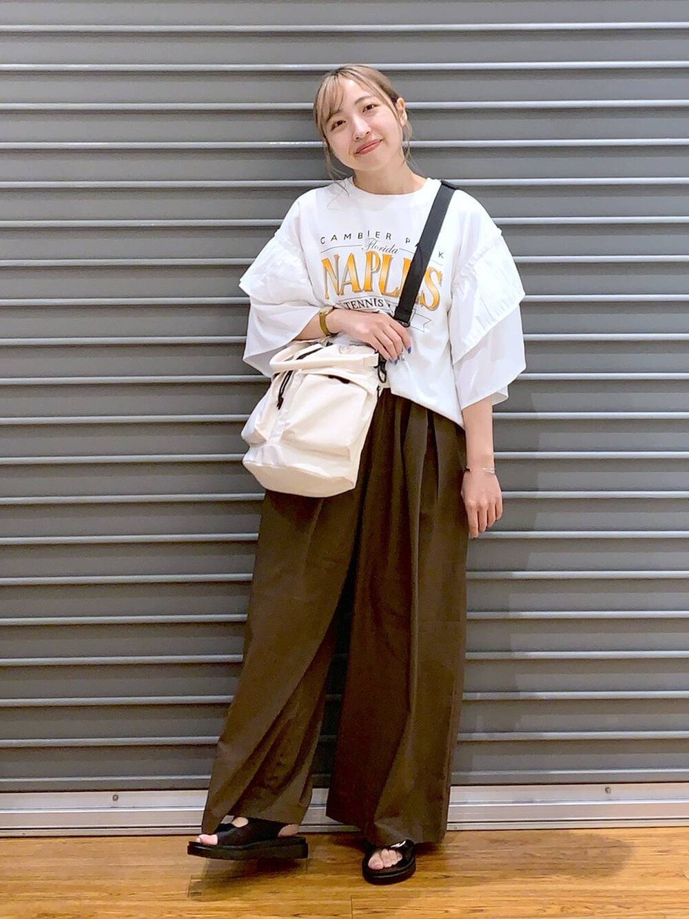 ホワイト系のショルダーバッグ、ブラック系のサンダル、ブラウン系のスラックスを着用したレディースの夏コーディネートの5枚目の写真