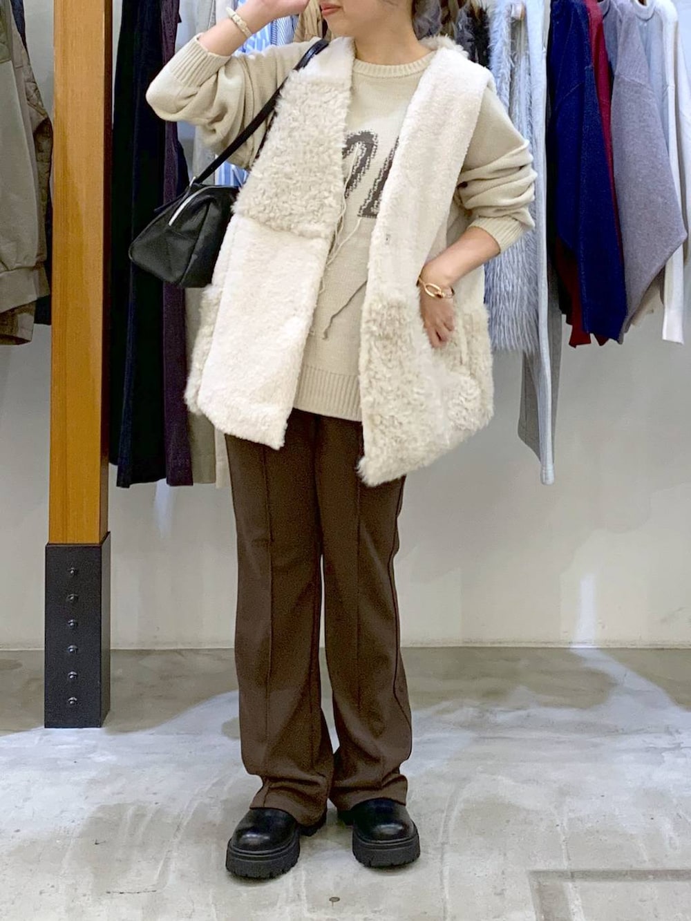 ブラウン系のその他パンツ、ブラック系のボストンバッグ、ホワイト系のベストを着用したレディースの秋コーディネートの7枚目の写真