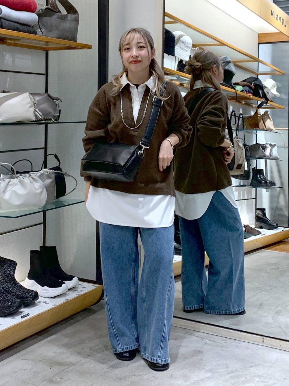 ブラック系のショルダーバッグ、ブラック系のブーツ、ブルー系のデニムパンツを着用したレディースの冬コーディネートの4枚目の写真