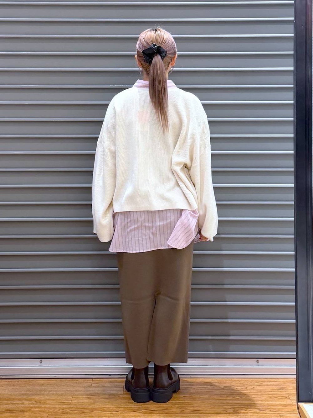 ブラウン系のスカート、ホワイト系のニット/セーター、ブラウン系のブーツを着用したレディースの冬コーディネートの2枚目の写真