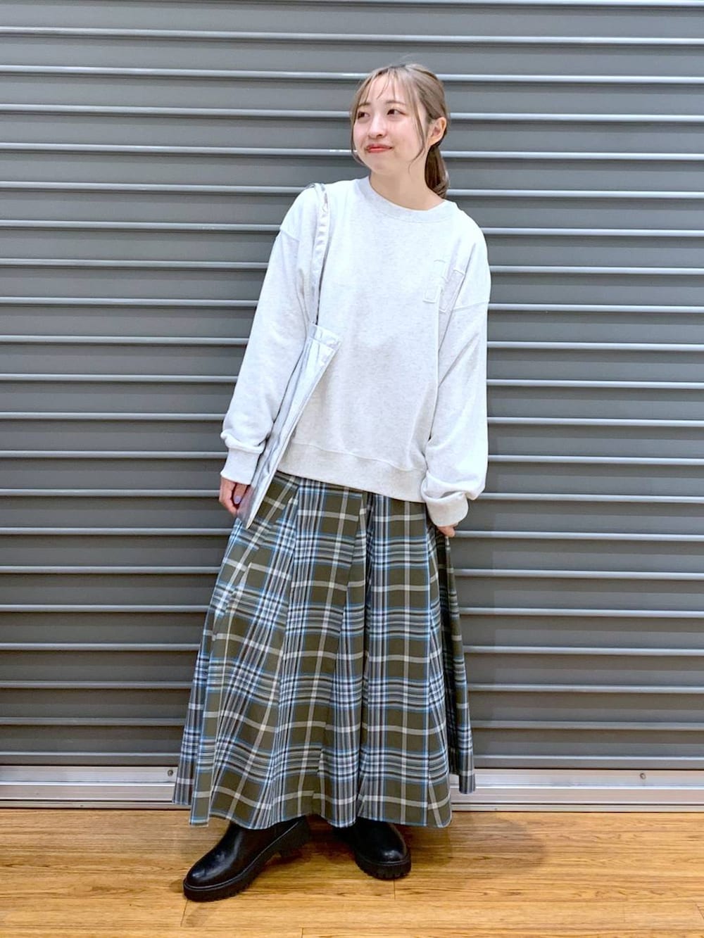 シルバー系のトートバッグ、ブラック系のブーツ、グリーン系のスカートを着用したレディースの冬コーディネートの7枚目の写真