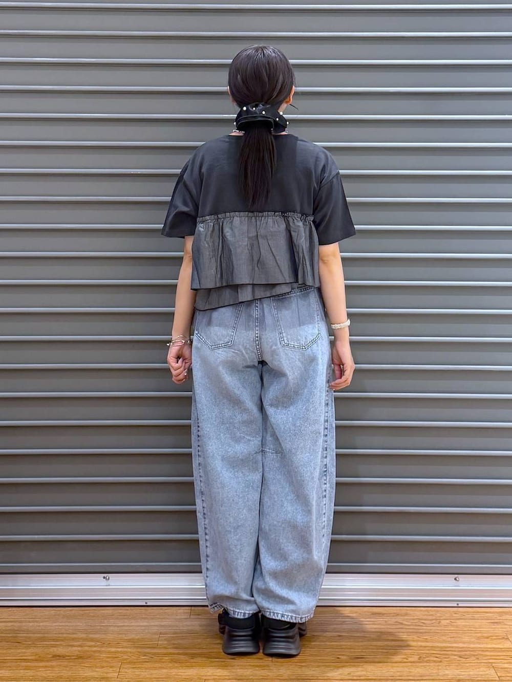 ブラック系のショルダーバッグ、ブラック系のサンダル、グレー系のTシャツ/カットソーを着用したレディースの夏コーディネートの2枚目の写真