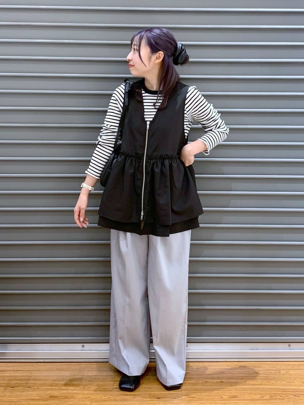 ブラック系のショルダーバッグ、ブラック系のパンプス、ブラック系のベストを着用したレディースの春コーディネートの3枚目の写真