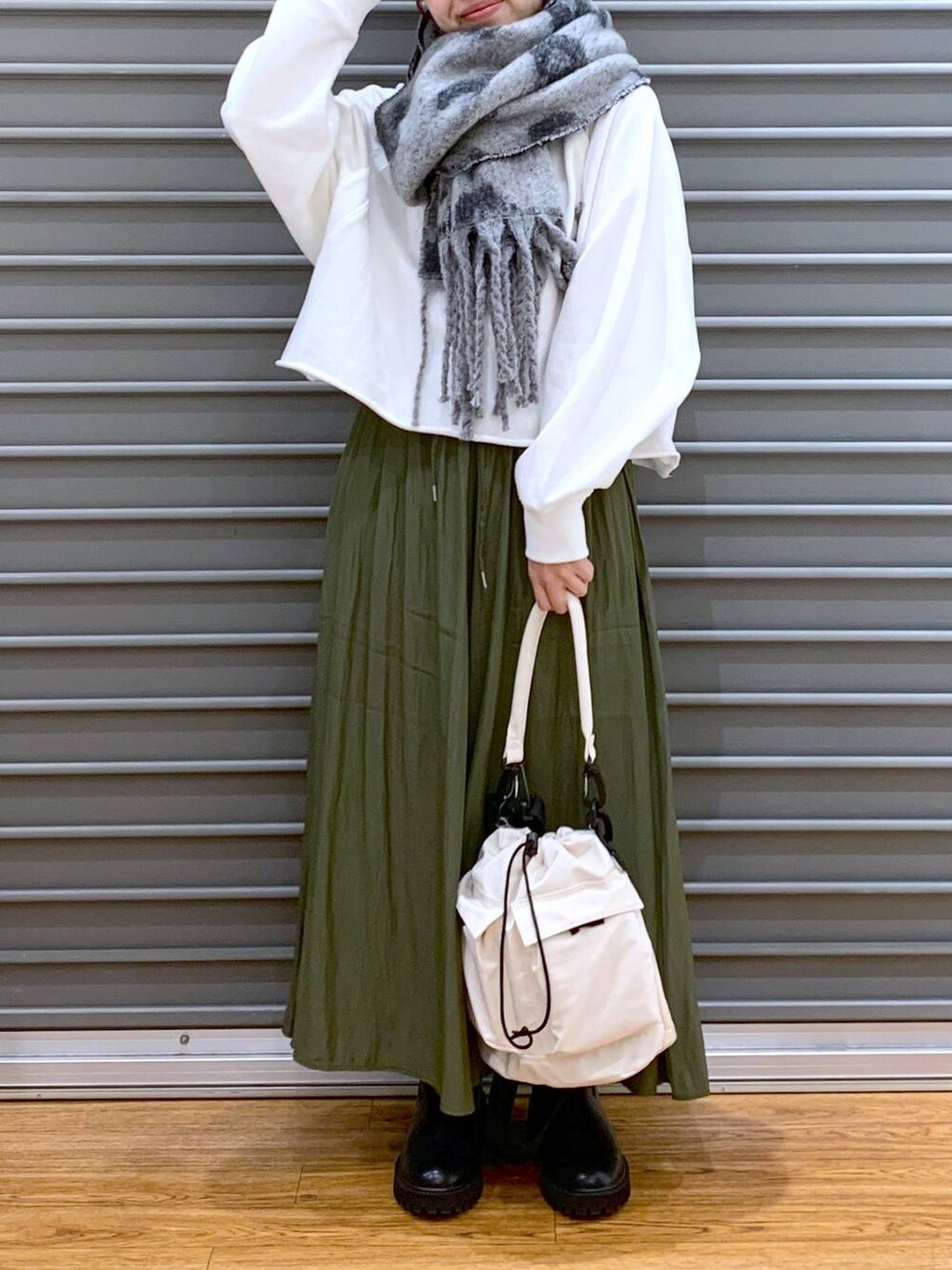 ホワイト系のショルダーバッグ、ブラック系のブーツ、ホワイト系のTシャツ/カットソーを着用したレディースの秋コーディネートの6枚目の写真