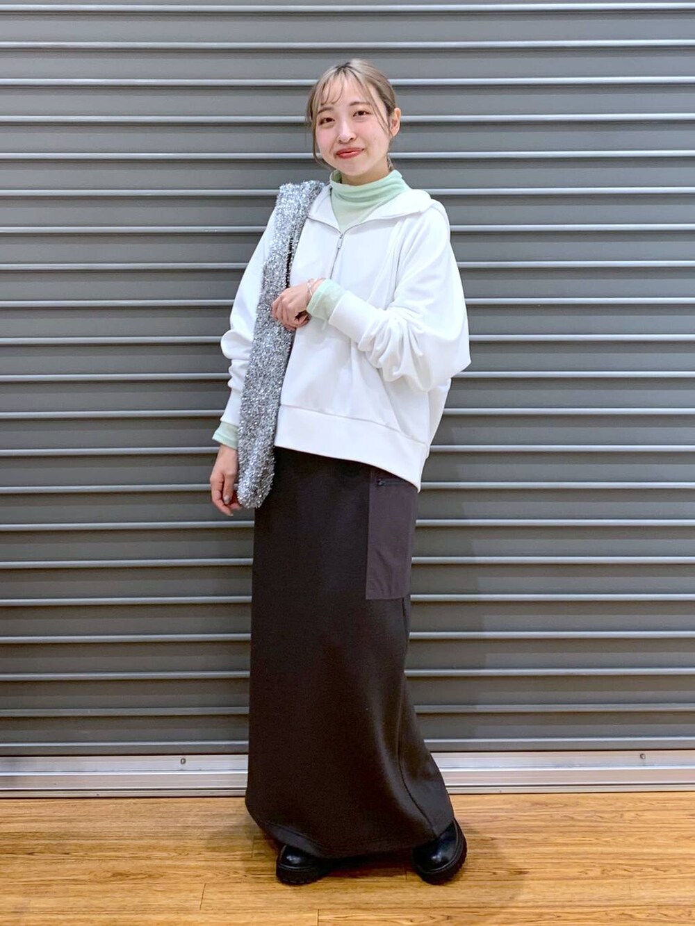 ブラック系のブーツ、シルバー系のショルダーバッグ、グレー系のスカートを着用したレディースの冬コーディネートの7枚目の写真