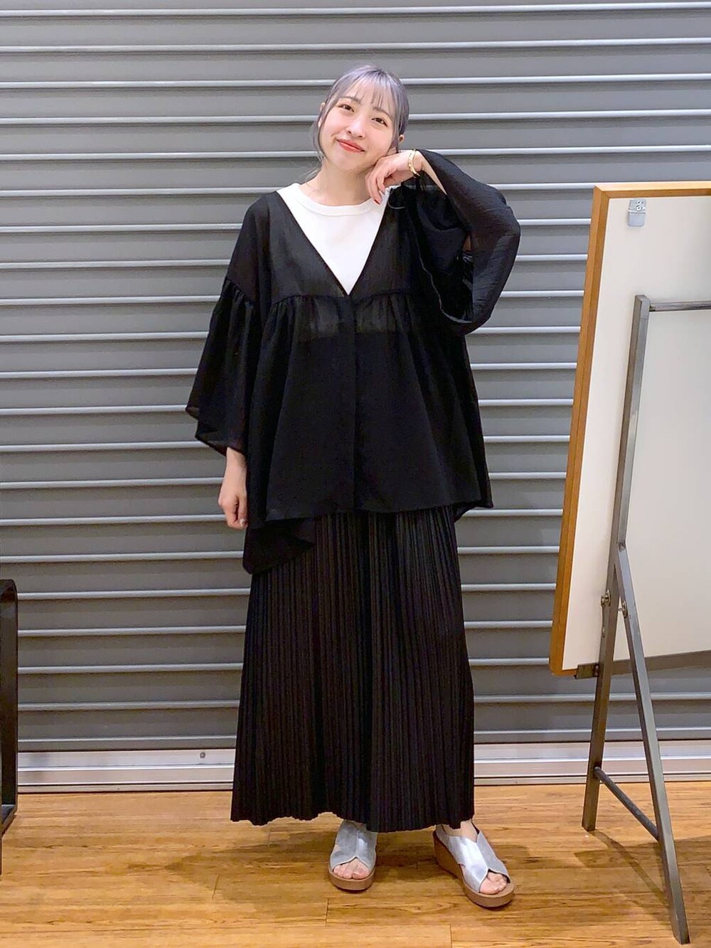 ブラック系のスカート、ブラック系のハンドバッグ、シルバー系のサンダルを着用したレディースの夏コーディネートの4枚目の写真