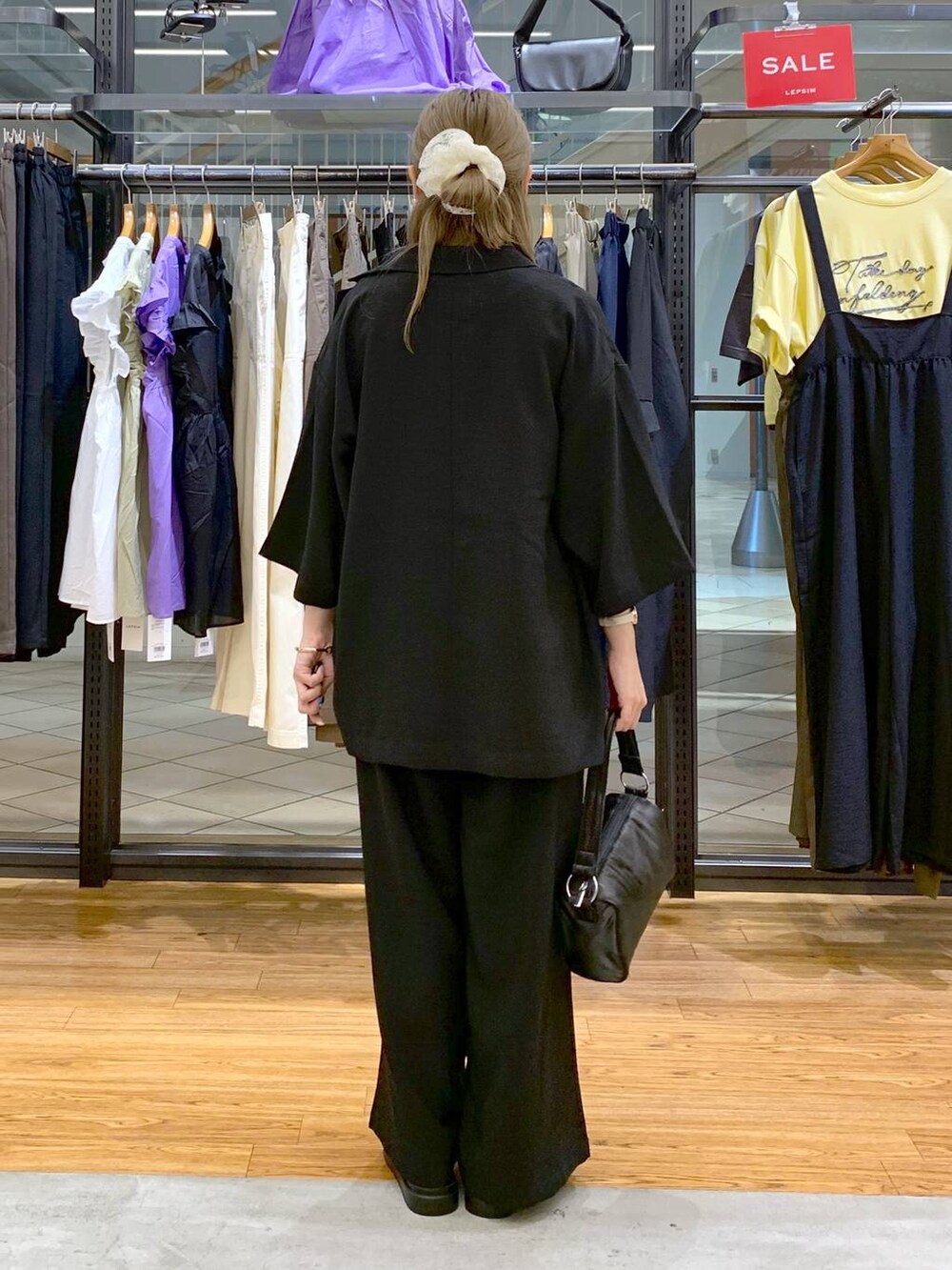 ブラック系のテーラードジャケット、ブルー系のタンクトップ、ブラック系のサンダルを着用したレディースの夏コーディネートの2枚目の写真