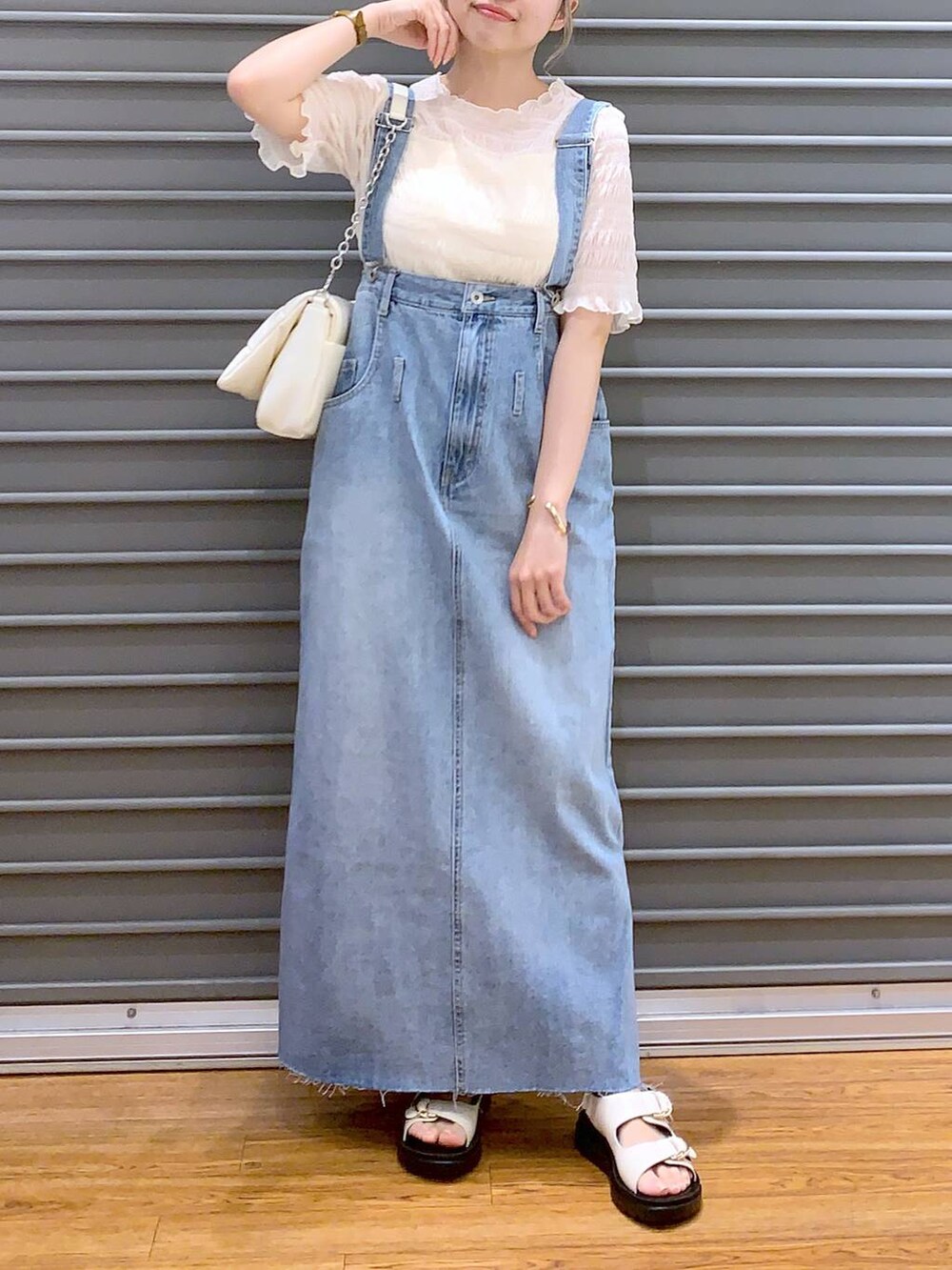 ホワイト系のショルダーバッグ、ホワイト系のキャミソール、ブルー系のジャンパースカートを着用したレディースの春コーディネートの4枚目の写真