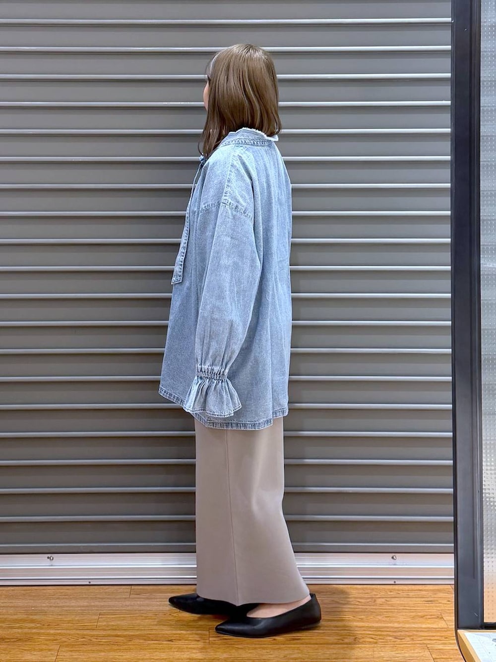 グレー系のスカート、ブラック系のパンプス、シルバー系のショルダーバッグを着用したレディースの春コーディネートの3枚目の写真