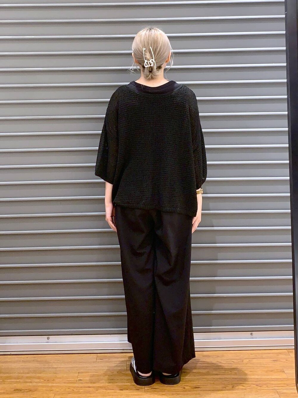 シルバー系のサンダル、ブラック系のスラックス、ブラック系のニット/セーターを着用したレディースの夏コーディネートの2枚目の写真