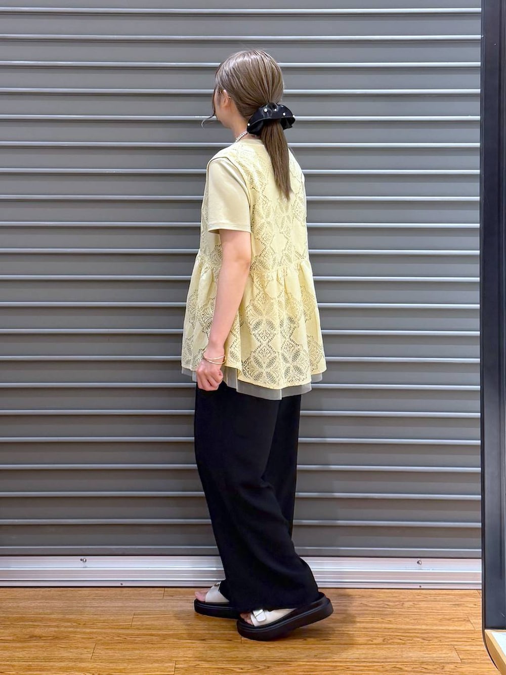 ブラック系のトートバッグ、ホワイト系のサンダル、ベージュ系のTシャツ/カットソーを着用したレディースの夏コーディネートの3枚目の写真