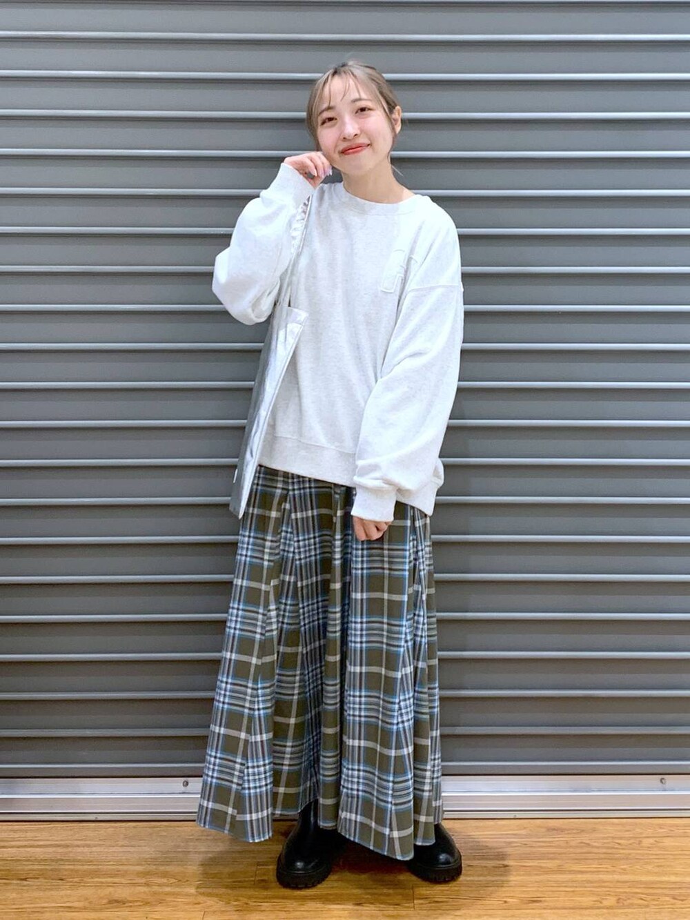 シルバー系のトートバッグ、ブラック系のブーツ、グリーン系のスカートを着用したレディースの冬コーディネートの3枚目の写真