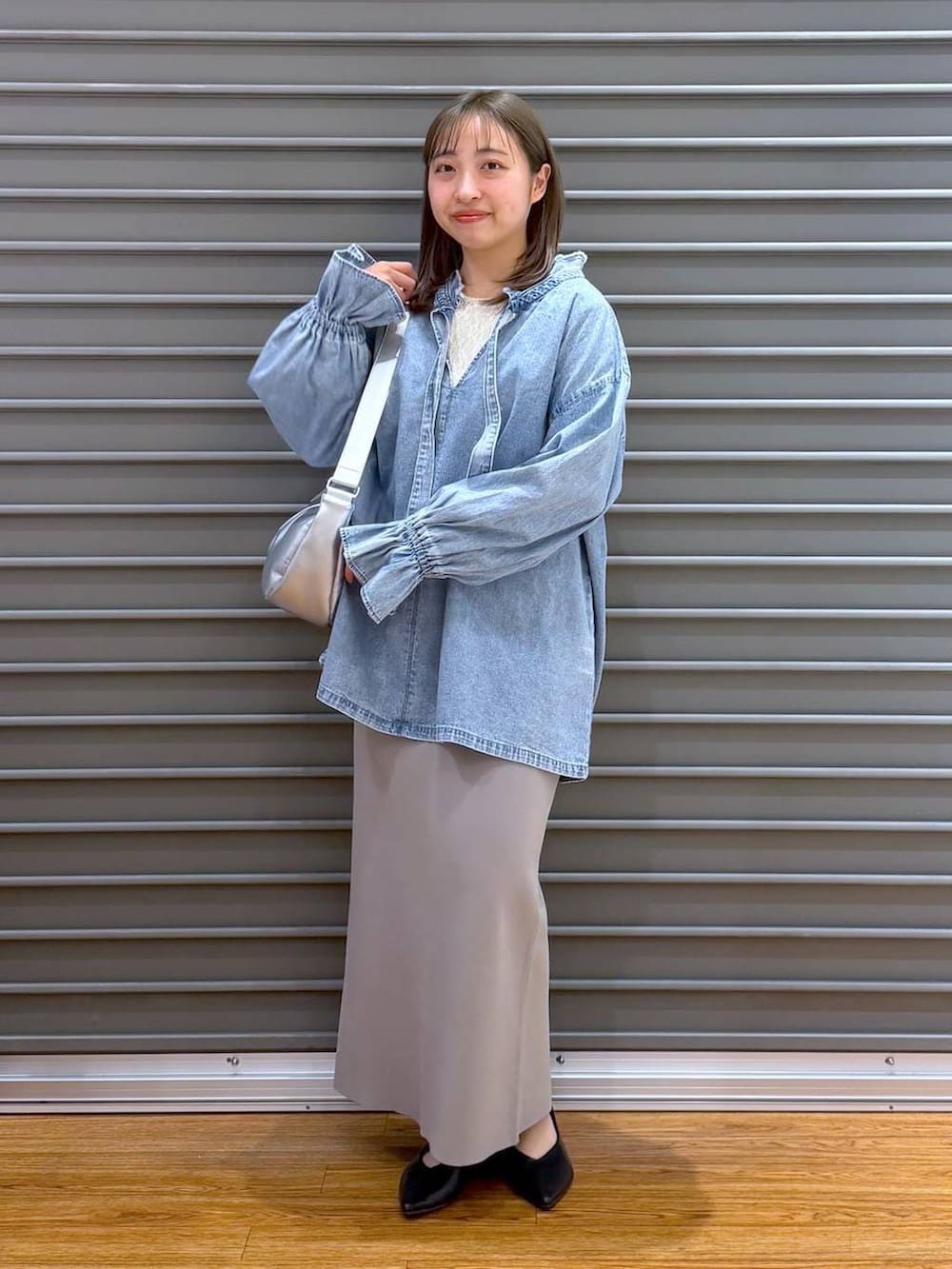 グレー系のスカート、ブラック系のパンプス、シルバー系のショルダーバッグを着用したレディースの春コーディネートの5枚目の写真