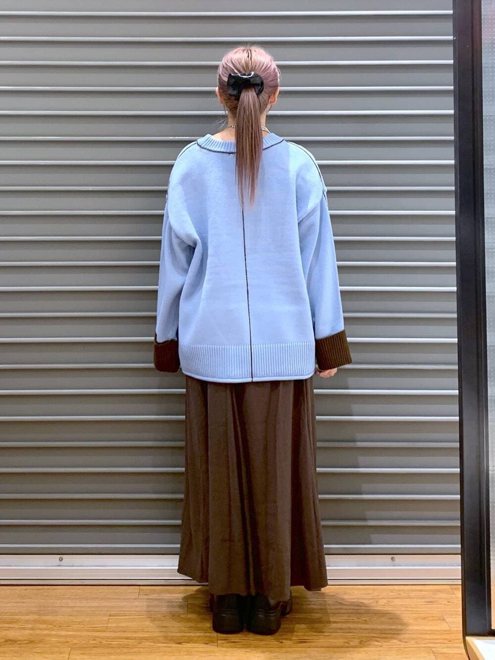 ブラック系のボストンバッグ、ブラック系のブーツ、ブラウン系のスカートを着用したレディースの冬コーディネートの2枚目の写真